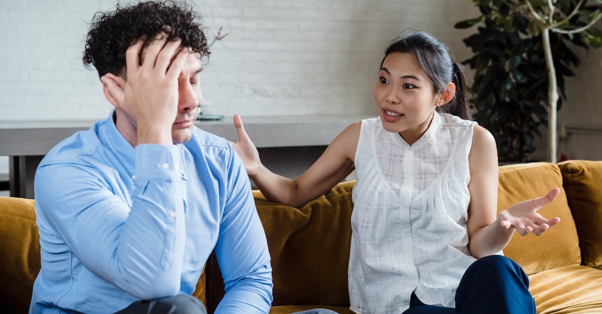 A couple having a serious conversation while sitting on a couch indoors.