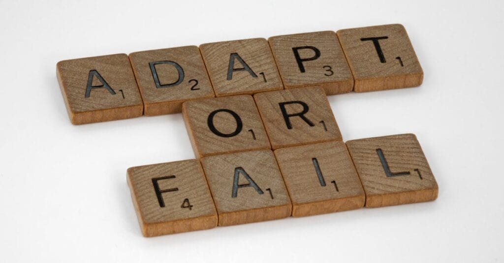 Scrabble tiles spell 'Adapt or Fail' on a white background, conveying a motivational message.