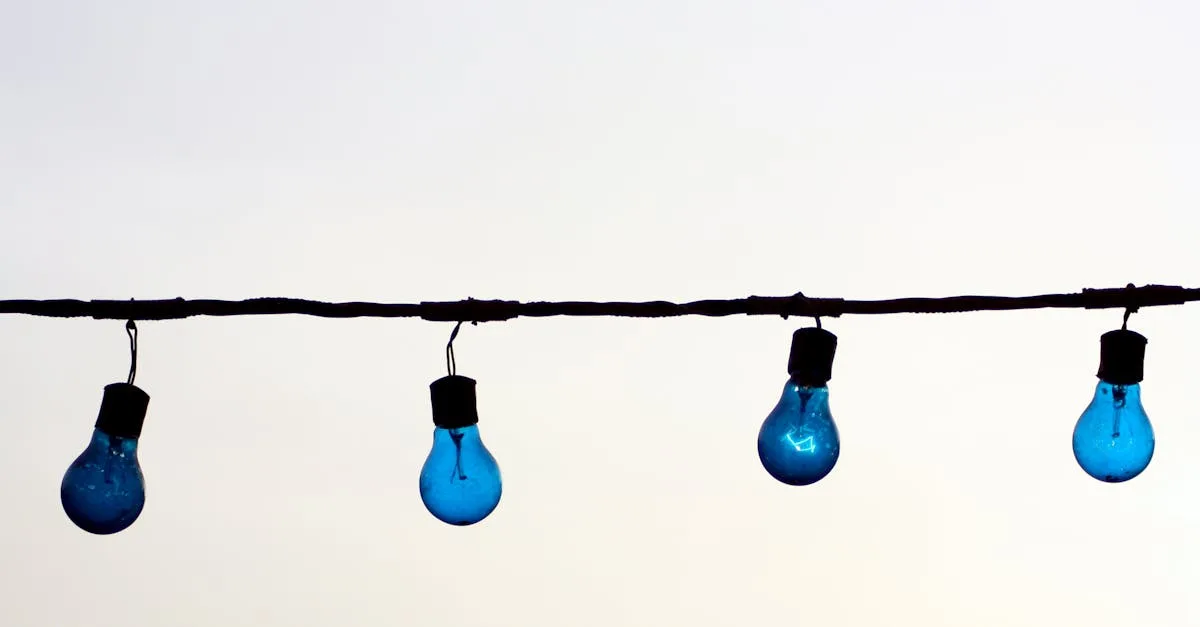 Minimalist image of blue light bulbs hanging on a wire against a neutral sky background, offering creative copyspace.