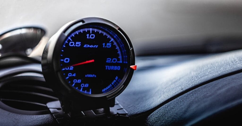 Close-up of a car turbo gauge inside a vehicle, displaying pressure levels.