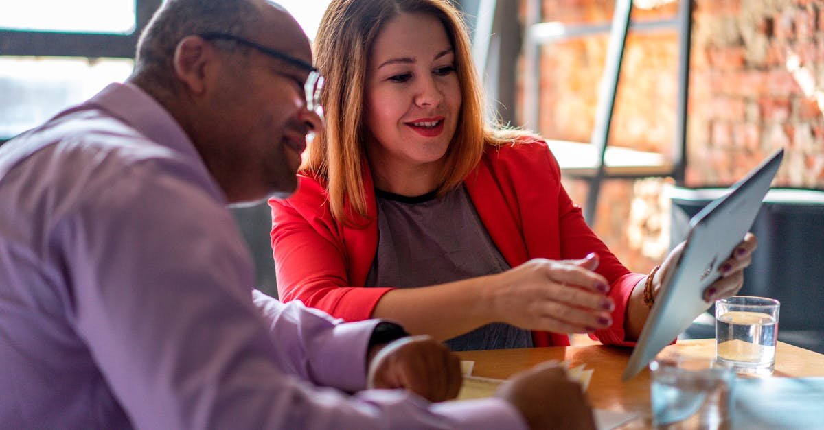 Two adults engaged in a productive conversation using a tablet in a modern office setting.