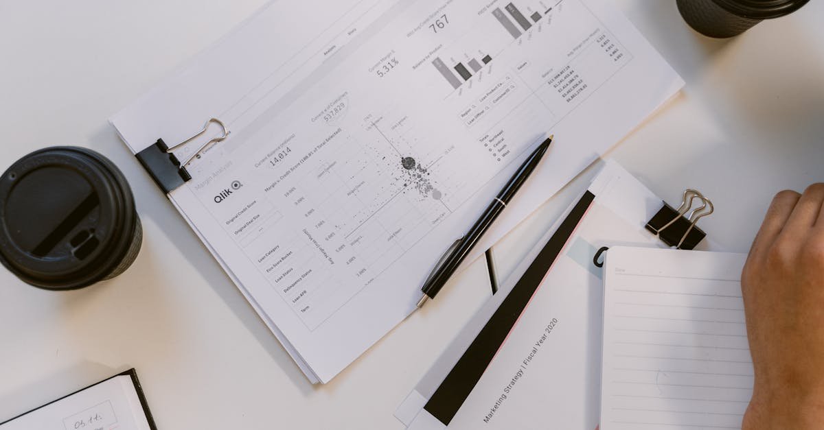 Overhead view of business reports and charts in a modern office setup on a white table.