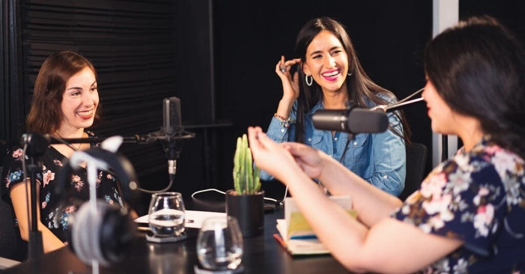 Three women enjoying a lively podcast discussion in a professional studio setting.