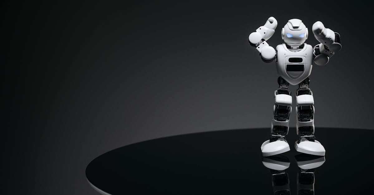 A small humanoid robot with glowing eyes on a reflective table in a dark setting.