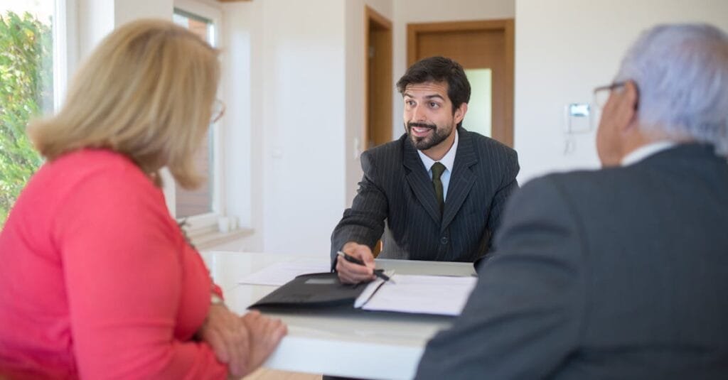 A real estate agent discussing a deal with senior clients in an office setting.